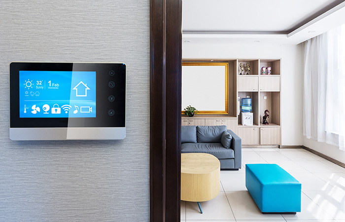 Intelligenter Touch-Screen für Smart Home an einer Wand mit Wohnzimmer im Hintergrund