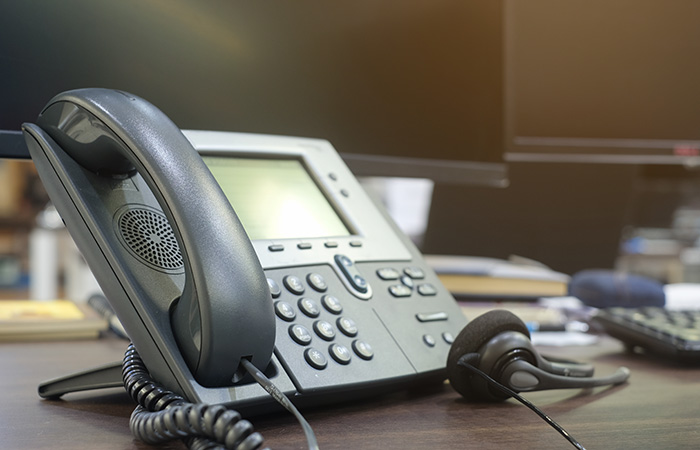 Telefonanlage mit Kopfhörern auf einem Schreibtisch vor unscharfem Hintergrund